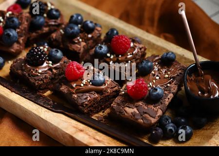 Makro. Brownie-Kuchen mit Beeren und Schokolade darauf. Köstliches Schokoladendessert. Stockfoto