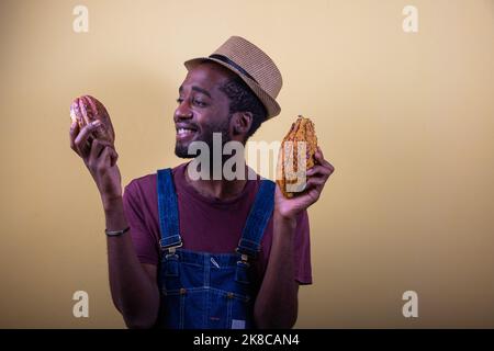 Ein afrikanischer Bauer schaut zufrieden mit seinen frisch geernteten Kakaoschoten, Foto im Studio Stockfoto