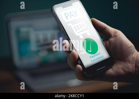 Junger Mann, der die elektronische Zahlung auf dem Mobiltelefon verwendet, der Kunde hält das Smartphone und führt eine digitale Zahlungstransaktion durch. Stockfoto