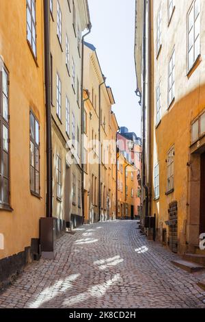 Helle Sonnenstrahlen auf einer schmalen Straße im historischen Teil von Stockholm. Altmodisches Gebäude in Gamla Stan, einem alten Teil der Stadt. Schweden. Stockfoto