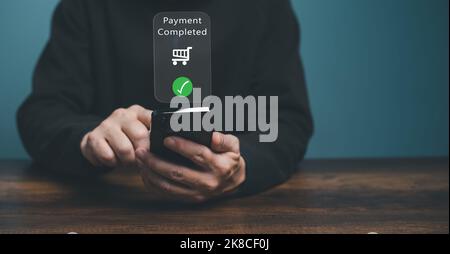 Junger Mann, der die elektronische Zahlung auf dem Mobiltelefon verwendet, der Kunde hält das Smartphone und führt eine digitale Zahlungstransaktion durch. Stockfoto