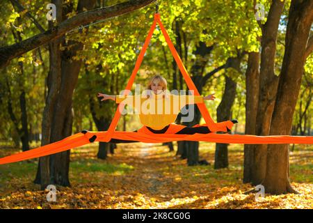 Frau, die im Herbst auf einem Baumhintergrund Luftseide übt Stockfoto