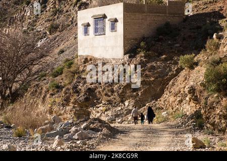 Berber Vater, Mutter und Kind wandern auf einer felsigen Straße im Hohen Atlas, im Ourika-Tal, Marokko, Nordafrika Stockfoto