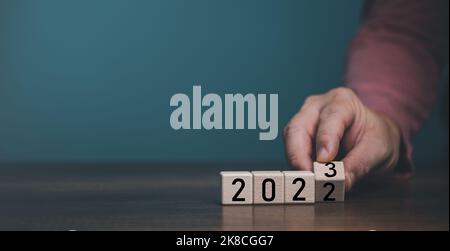 Hölzerner Würfel Block Flipping Countdown von 2022 bis 2023 auf blauem Hintergrund, Vorbereitung für fröhliche Weihnachten und glückliches neues Jahr Konzept. Stockfoto