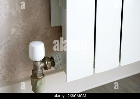 Heizkörper mit Thermostat an der Hauswand, weißer Metallwassererhitzer im Hauszimmer. Konzept von Wärme, Energiekrise, Einsparung, moderne Heizkörper Stockfoto