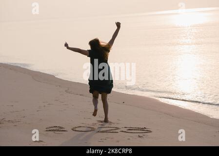 2023 Frohes Neues Jahr, Junge gesunde Frau beim Sonnenaufgang am Strand laufen und springen, Gesundheitswesen, Krankenversicherung, gesundes Lebenskonzept, Kopierraum Stockfoto