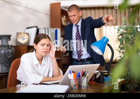 Ein junger Geschäftsmann schimpft sein Mädchen im Büro Stockfoto