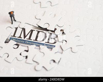 Illustrative Editorial von 1MDB Skandal Konzept - 1Malaysia Entwicklung Berhad kriminellen Fall-Miniatur-Figur eines Geschäftsmannes Blick auf Rätsel. Stockfoto