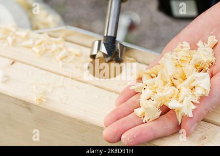 Zimmermann bohrt Löcher in den Holzbalken. Holzrahmen Hausgebäude Stockfoto