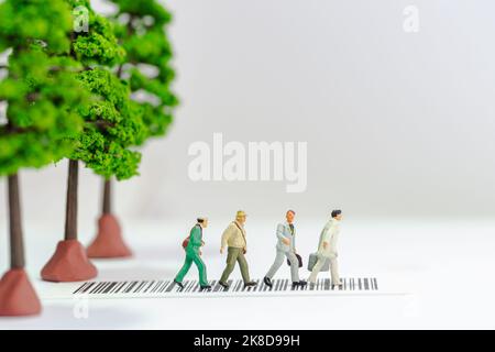 Miniatur-Spielzeug eine Gruppe von Menschen, die eine Straße mit Baumspielzeug auf dem Bürgersteig überqueren - Straßensicherheitskonzept. Stockfoto