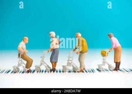 Miniatur-Spielzeug eine Gruppe alter Menschen mit Rollstuhl über eine Straße - Straßenverkehrssicherheit Konzept für Senioren. Stockfoto