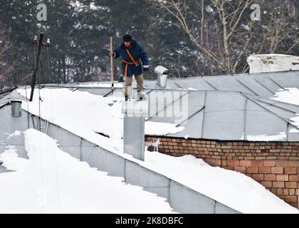 Schneeentferner arbeitet auf dem Dach Stockfoto