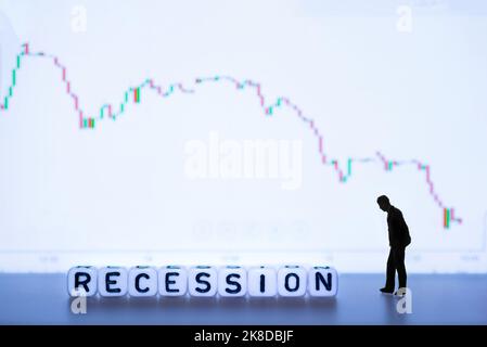 Miniaturfiguren Silhouette - wirtschaftliche Abschwächung oder Rezession Konzept mit Abwärtsdiagramm im Hintergrund. Stockfoto