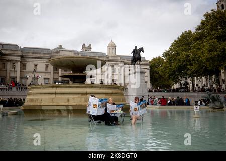 London, Großbritannien. 22. Oktober 2022. Aktivisten sahen, wie sie einen gefälschten The Guardian mit einem Tofu-Tisch im Brunnenbereich am Trafalgar Square lasen. Aktivisten von Animal Rebellion haben eine Performance Arts am Brunnen auf dem Trafalgar Square inszeniert, als Reaktion auf das Zitat der ehemaligen Innenministerin Suella Braverman im britischen Parlament, das „Guardian-reading, tofu-eating wokerati“ zitiert wurde. (Foto von Hesther Ng/SOPA Images/Sipa USA) Quelle: SIPA USA/Alamy Live News Stockfoto