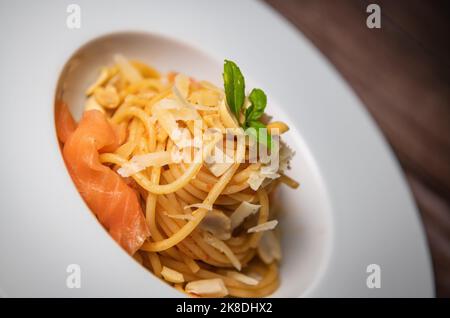 Rezept für hausgemachte Spaghetti mit Tomatensauce, geräuchertem Lachs, gerösteten Erdnüssen und Parmesan Stockfoto