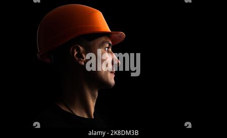 Schmutziges Gesicht des Kohlebergarbeiters auf schwarzem Hintergrund. Kopf eines müden Bergarbeiters in einem Hut. Stockfoto