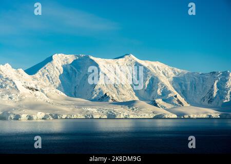 Am frühen Morgen leuchtet die Sonne auf dem schneebedeckten Gipfel des francois auf der insel anvers vom neumayer-Kanal. antarktische Halbinsel. antarktis Stockfoto