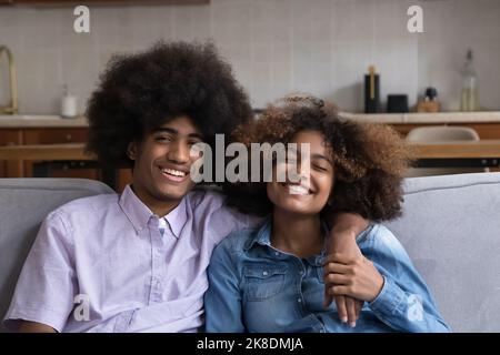 Afrikanisches Teenager-Paar sitzt auf dem Sofa Lächeln Blick auf die Kamera Stockfoto