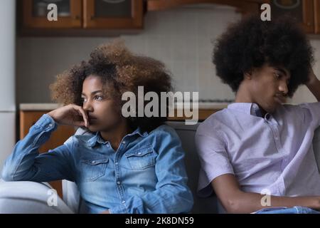 Trauriges afrikanisches Paar sitzt auf dem Sofa und fühlt sich nach dem Streit aufgeregt Stockfoto