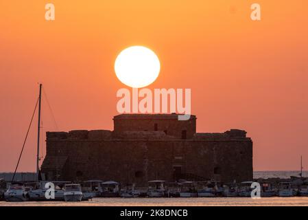 Die Sonne untergeht über dem Fort von Pafos, dem Hafen von Pafos, Zypern. Stockfoto