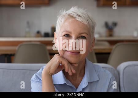 Attraktive Frau mittleren Alters sitzt auf der Couch, Kopf geschossen Porträt Stockfoto