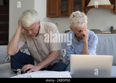 Das ältere Paar sieht besorgt nach der Analyse der Familienfinanzen aus Stockfoto