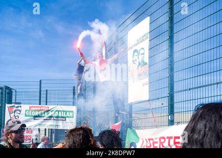 Ein Mann mit einer Rauchbombe auf dem Zaun des Gefängnisses mit Plakaten herum. Jährliche Demonstration für die Freilassung von Georges Abdallah vor dem Gefängnis, in dem er in Lannemezan auf Aufruf vieler Unterstützungskomitees, Verbände, Gewerkschaften und politischer Parteien festgehalten wird. Georges Ibrahim Abdallah, ein Aktivist der palästinensischen Sache, ist seit 38 Jahren in Frankreich inhaftiert! Er ist in Lannemezan inhaftiert. Frankreich, Lannemezan am 22. Oktober 2022. Foto von Patricia Huchot-Boissier / ABACAPRESS.COM Stockfoto