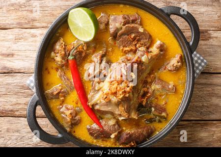 Gulai Kambing oder indonesische traditionelle köstliche Ziegencurry in der Pfanne auf dem Holztisch. Horizontale Draufsicht von oben Stockfoto