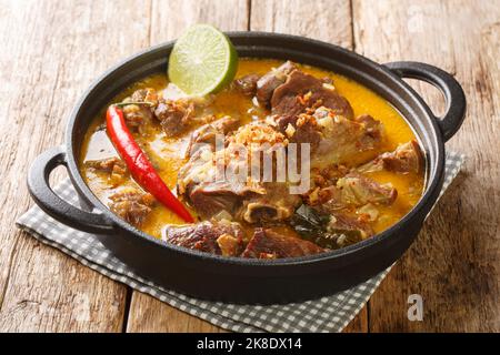 Indonesisches Essen Gulai Kambing Ziegenkurvig würziger Eintopf aus der Nähe auf der Pfanne auf dem Holztisch. Horizontal Stockfoto