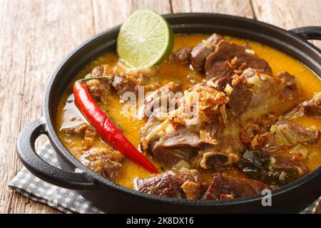 Gulai Kambing oder indonesische traditionelle köstliche Ziegencurry in der Pfanne auf dem Holztisch. Horizontal Stockfoto