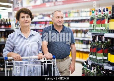 Reifes Paar Ehemann und Ehefrau wählen alkoholische Getränke im Supermarkt Stockfoto