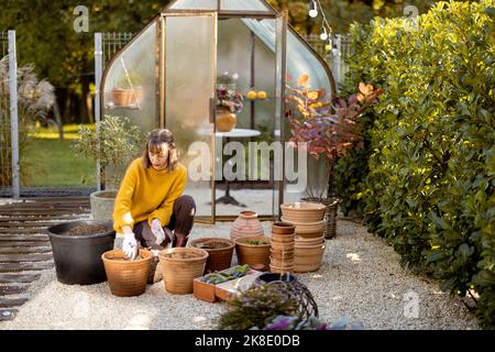 Frau pflanzt Blumen in Krügen im Garten Stockfoto