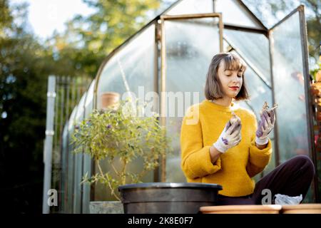 Frau pflanzt Blumen in Krügen im Garten Stockfoto