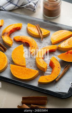 Kürbis in Scheiben geschnitten mit Zimt auf Backblech Kochen Lebensmittel Stockfoto