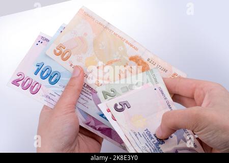 Hand hält die Turksh Lira Banknoten auf weißem Hintergrund Stockfoto