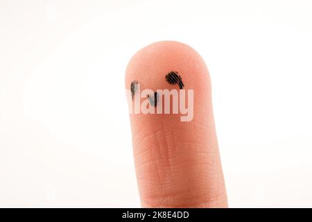 Schwarze Punkte, die ein Gesicht auf der Fingerspitze bilden Stockfoto