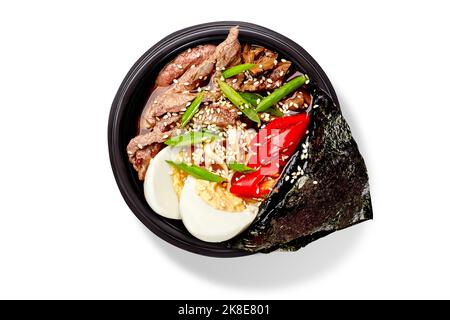 Würzige Ramen-Suppe mit Nudeln, Rindfleisch, Shiitake-Champignons, gekochtem Ei, rotem Paprika, Grüne Zwiebel, Sesam und Nori Stockfoto