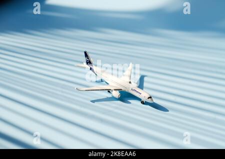 Draufsicht auf Spielzeug Flugzeug vor blauem Hintergrund Nahaufnahme. Flach liegend. Urlaub, Reise, Reisekonzept. Stockfoto