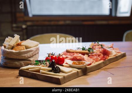 Menschen, die Wein trinken und kaltes Fleisch in einem Weinkeller essen. Stockfoto