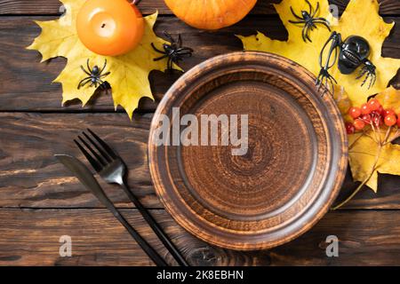 Draufsicht auf leeren halloween Teller mit Kürbissen auf einem rustikalen Tisch. Halloween Tischunterlage mit Besteck. Festliches Konzept. Stockfoto