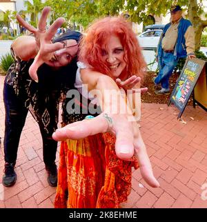 Santa Barbara, CA, Santa Barbara. 22. Oktober 2022. Red Head Woman mit ausgestreckter Hand trifft am Samstag, den 22. Oktober, auf der State Street in Santa Barbara, CA, auf die tanzenden Zombies von Flash Mob und den World Dance for Humanity. Sie werden am kommenden Wochenende mehr Flash-Mob-Aktivitäten im Vorlauf zum großen Event machen. 29.. Oktober: Wenn über 150 Menschen sich wie Zombies aus Michael Jacksons Thriller-Video kleiden und gemeinsam in den Santa Barbara Court Sunken Gardens tanzen werden. Seit 2010 veranstaltet World Dance for Humanity das THRILLER-Event von Santa Barbara als Teil eines globalen Tanzes Stockfoto