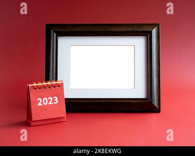 Vorlage für Fotorahmen für Karte mit kleinem roten Tischkalender mit 2023-Jahres-Nummer auf rotem Hintergrund, minimalistisch. Leerer weißer Leerraum im Vintage-Stil Stockfoto