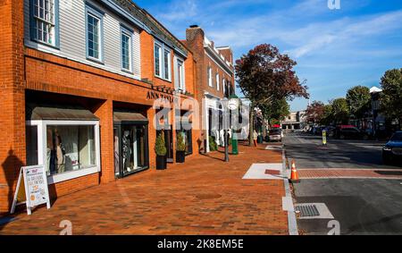 NEW CANAAN, CT, USA - 22. OKTOBER 2022: Backsteingebäude mit Fassade und Gehweg mit Ladenfronten und Stadtuhr Stockfoto