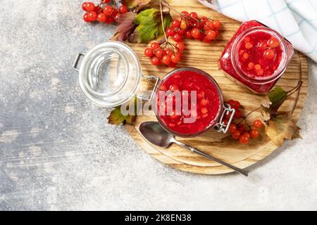 Frische reife Viburnum-Beere mit Zucker zur Zubereitung von Vitamin- und antioxidativem Tee auf einem Steintisch. Quelle von natürlichen Vitaminen. Wird in der Volksmedizin verwendet. Stockfoto