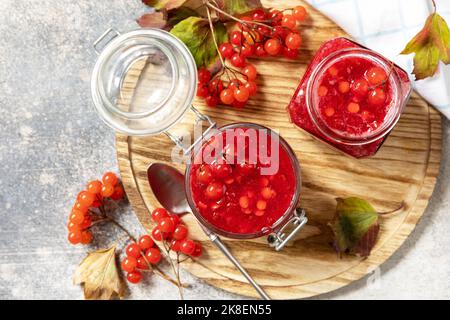 Frische reife Viburnum-Beere mit Zucker zur Zubereitung von Vitamin- und antioxidativem Tee auf einem Steintisch. Quelle von natürlichen Vitaminen. Wird in der Volksmedizin verwendet. Stockfoto