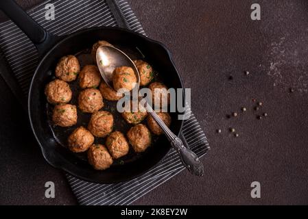 Fleischbällchen in einer schwarzen Bratpfanne auf dunklem Hintergrund Stockfoto