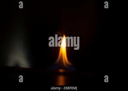 Flammen im Dunkeln. Zunge des Feuers eins. Flammhemmung durch Alkohol. Gelbes Leuchten auf schwarzem Hintergrund. Stockfoto