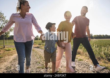 Glückliche Familie mit Händen durch die Natur spazieren Stockfoto