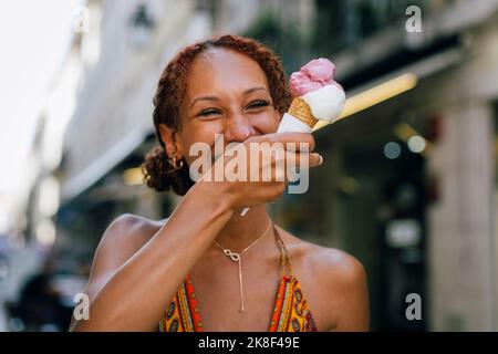 Fröhliche junge Frau, die Eis genießt Stockfoto
