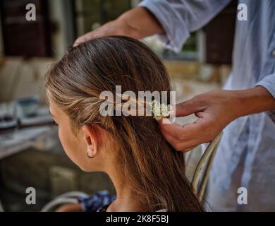 Frau, die Blume im Haar der Tochter anpasst Stockfoto